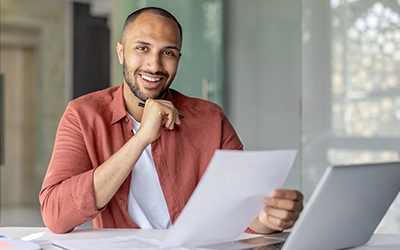 smiling man with papers and laptop