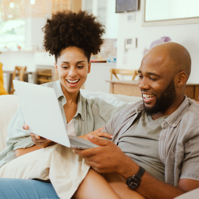 two people looking at laptop while sitting on couch